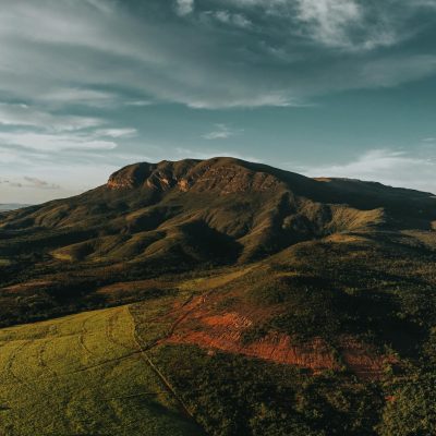 Breathtaking aerial shot of lush green hills and mountains under a dramatic sky at dawn.