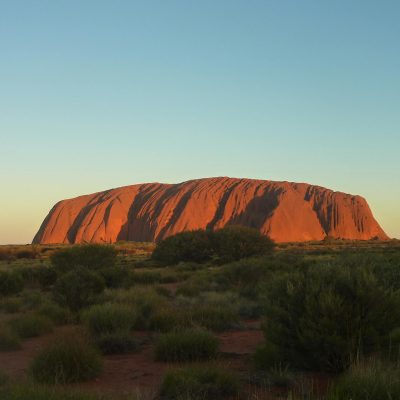 Capture the majestic Uluru rock formation glowing under the sunset. A natural wonder in Australia's Outback.