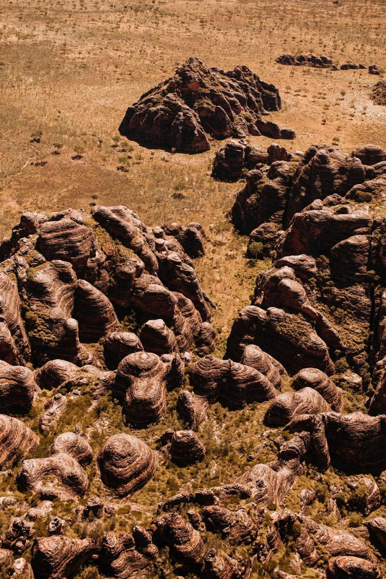 Landscape of dry valley with uneven rocks and hills near grass in semidesert in sunny summer day