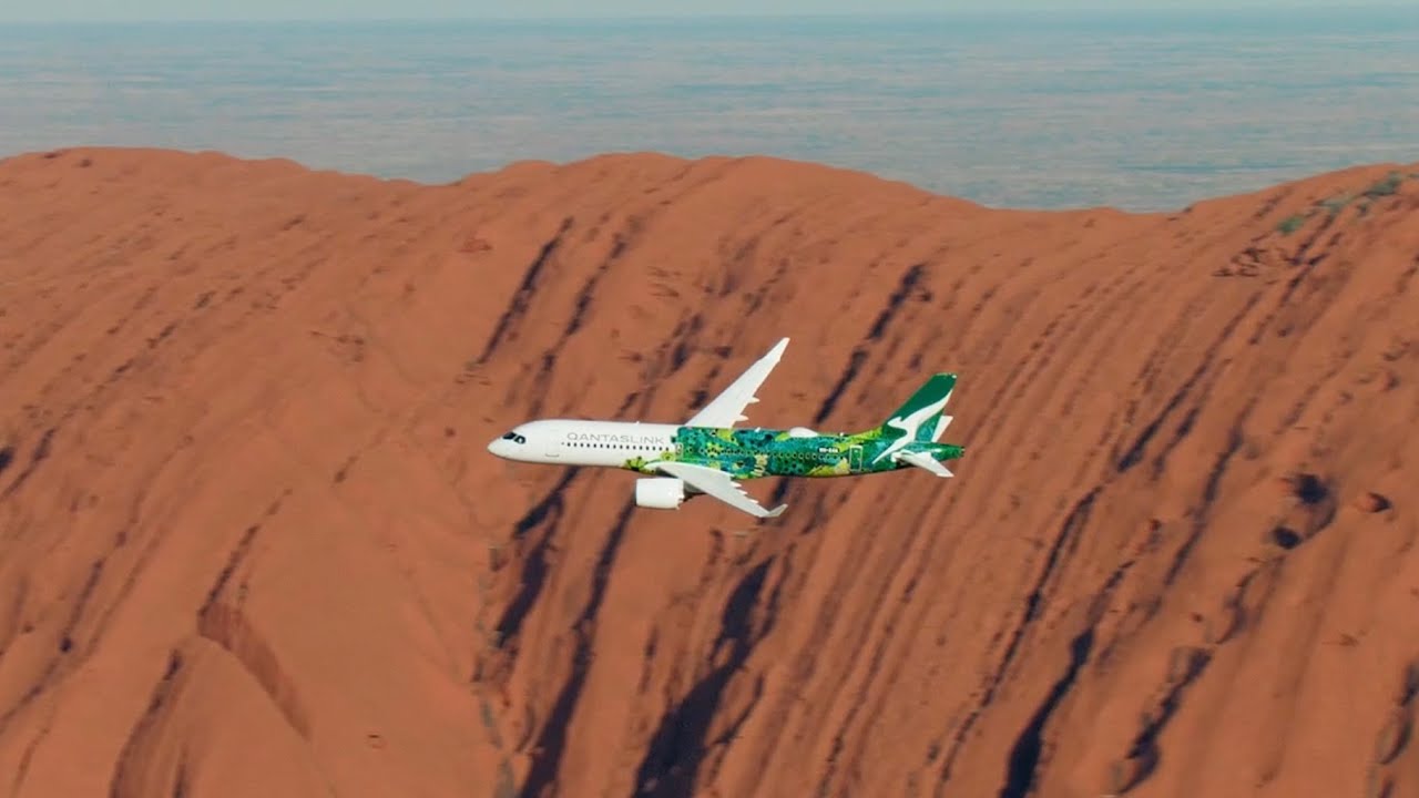 Commercial airplane landing at Ayers Rock Airport AYQ with Uluru in the background